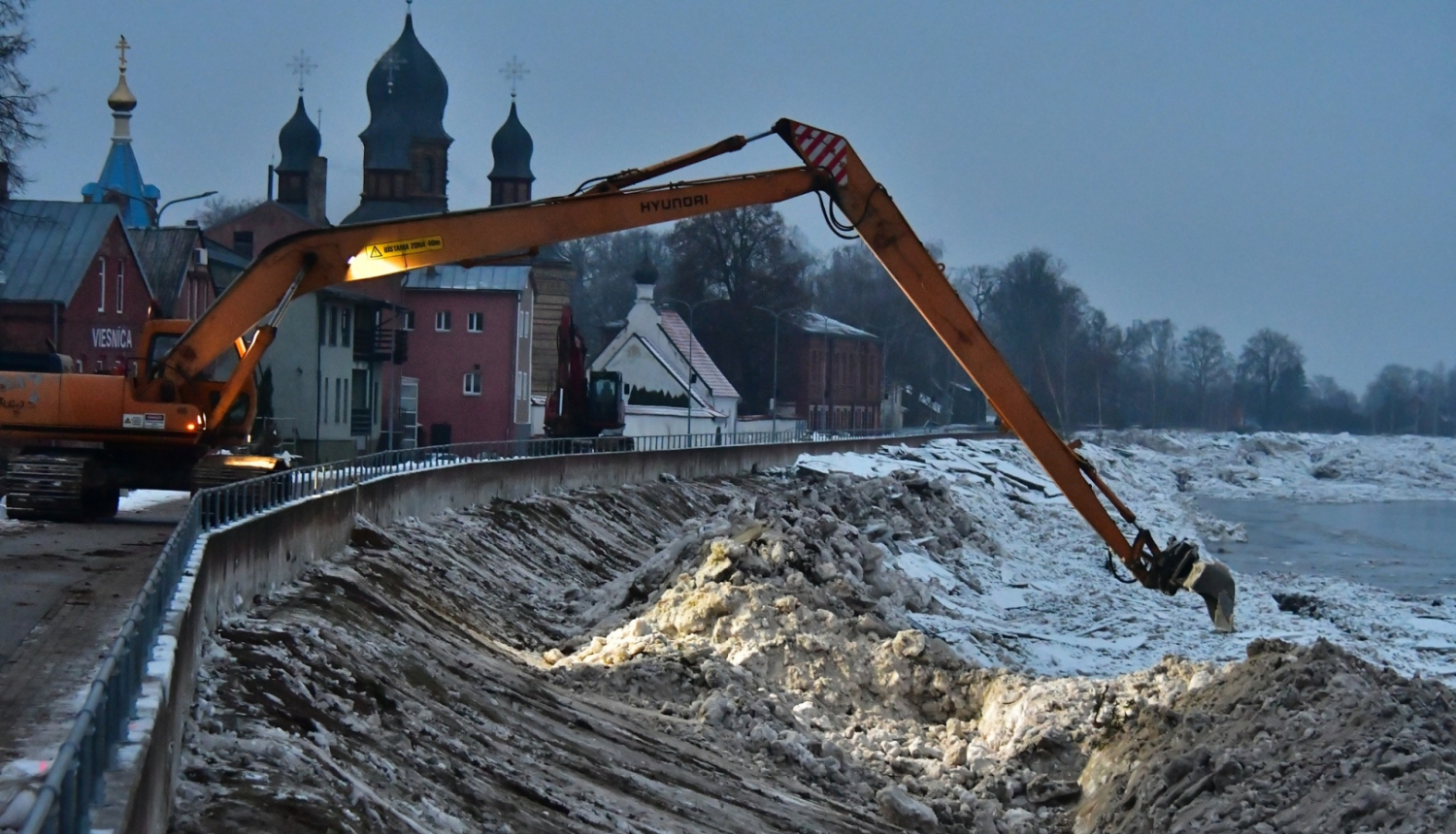 Ekskavators uz dambja pie Daugavas