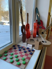 Uz palodzes stāv skolēnu pašu darinātas lietas - dambrete un kartona ģitāras