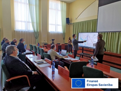 Civilās aizsardzības mācības sēžu zālē Krustpili, tiek rādīta karte uz ekrāna, komisijas locekļi skatās un spriež iespējamās darbības