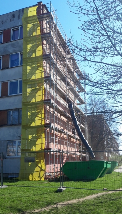 Daudzdzīvokļu māja pavasarī ar sastatnēm sānā