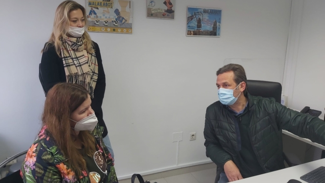 trīs personas telpā ar maskām sarunājas