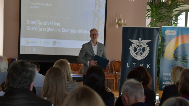 Vadītājs uzrunā publiku zālē