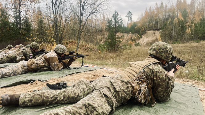Zemessargi pilnā ekipējumā guļus uz zemes trenējas šaušanā