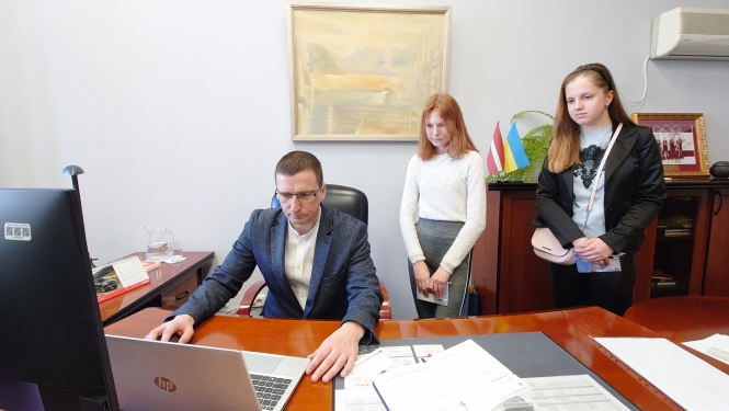 Priekšsēdētājs ar 2 ēnotājiem skolēniem darba kabinetā