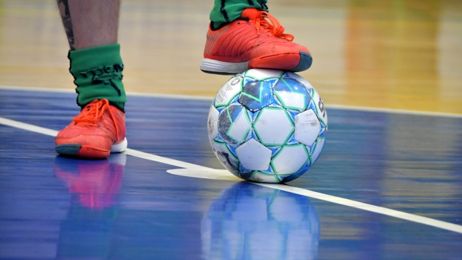Telpu futbola bumba uz grīdas, pēda piespiež