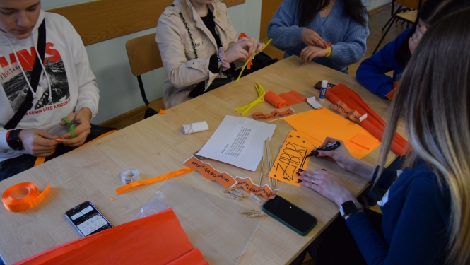 Jaunieši pie galda nodarbojas ar rokdarbiem