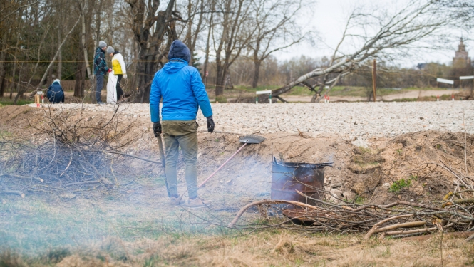 Publicitātes foto no 2021. gada, kurā cilvēks ceļa malā dedzina zaru čupu
