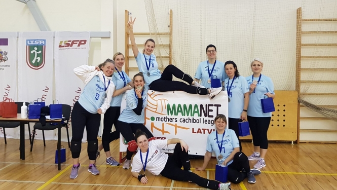 Mamanet komanda sporta zālē pozē kopbildei, turot pa vidu rokās mamanet plakātu