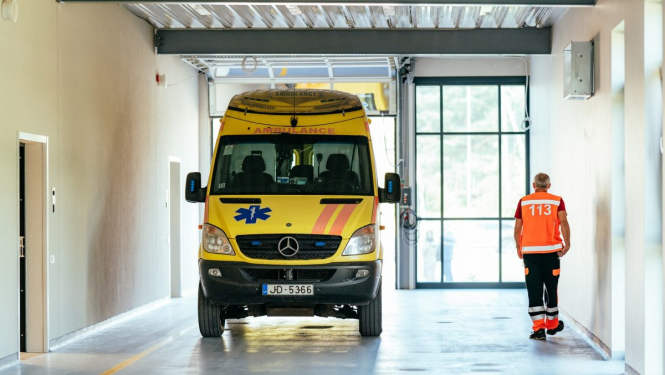 Slimnīcas pacientu uzņemšanas nodaļa - ātrās palīdzības auto un darbinieks blakus