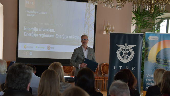 Vadītājs uzrunā publiku zālē