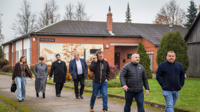 Deputāti iet pret kameru, fonā pagasta pārvaldes ēka