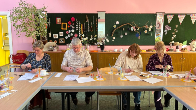 Četri skolotāji attēlā seminārā darbojas pie galda