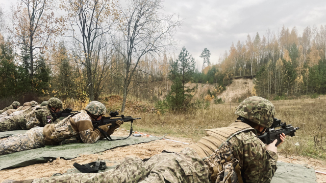Zemessargi pilnā ekipējumā guļus uz zemes trenējas šaušanā