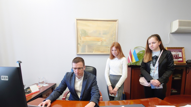 Priekšsēdētājs ar 2 ēnotājiem skolēniem darba kabinetā