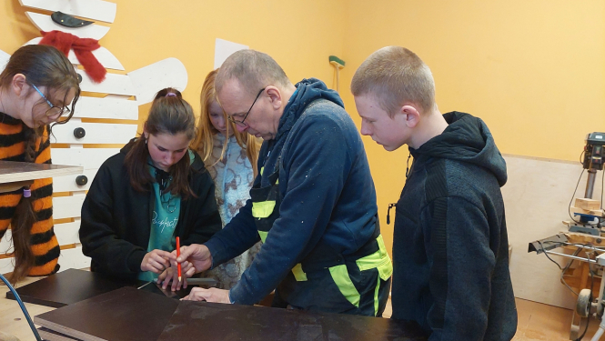 Skolēnu mājturības kabinetā vēro skolotāja darbības ar plāksni