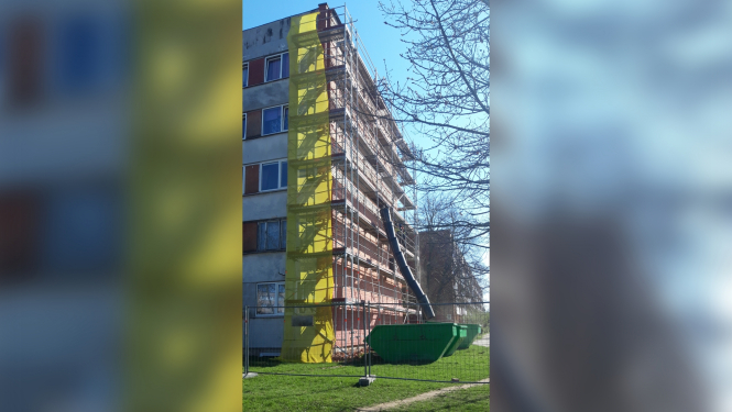 Daudzdzīvokļu māja pavasarī ar sastatnēm sānā