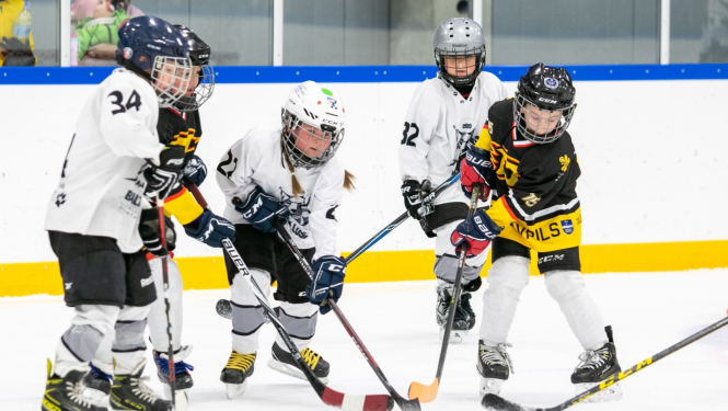 Roks & hokejs - publicitātes foto (4 mazie hokejisti cīnās uz ledus par ripu)
