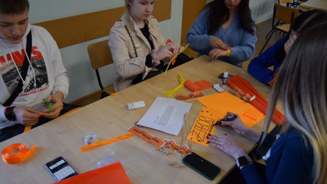 Jaunieši pie galda nodarbojas ar rokdarbiem