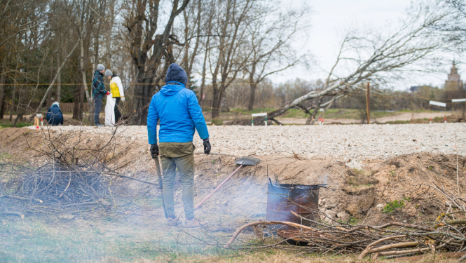 Publicitātes foto no 2021. gada, kurā cilvēks ceļa malā dedzina zaru čupu