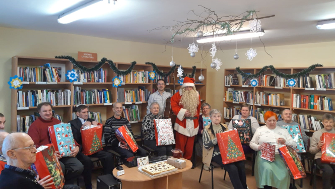 Pansijas Mežvijas iemītnieki ar saņemtajām Ziemassvētku dāvanām klēpī; centrā stāv muzikants Arnis Čakstiņš un Ziemassvētku vecītis