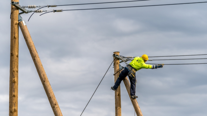 fotogrāfijā redzams elektriķis un elektrības stabi