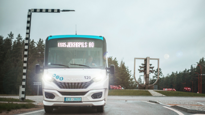 Balts auobuss iebrauc Jēkabpilī, fonā pilsētas ģerbonis