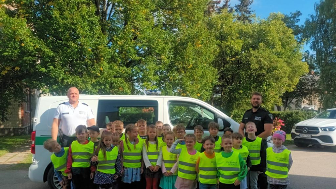 Pašvaldības policijas pārstāvji ar skolēniem pie policijas auto