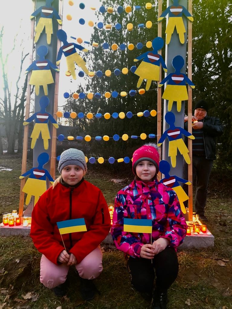 Bērni sēž pie saviem darbiem, kas tapuši atbalstam Ukrainas iedzīvotājiem