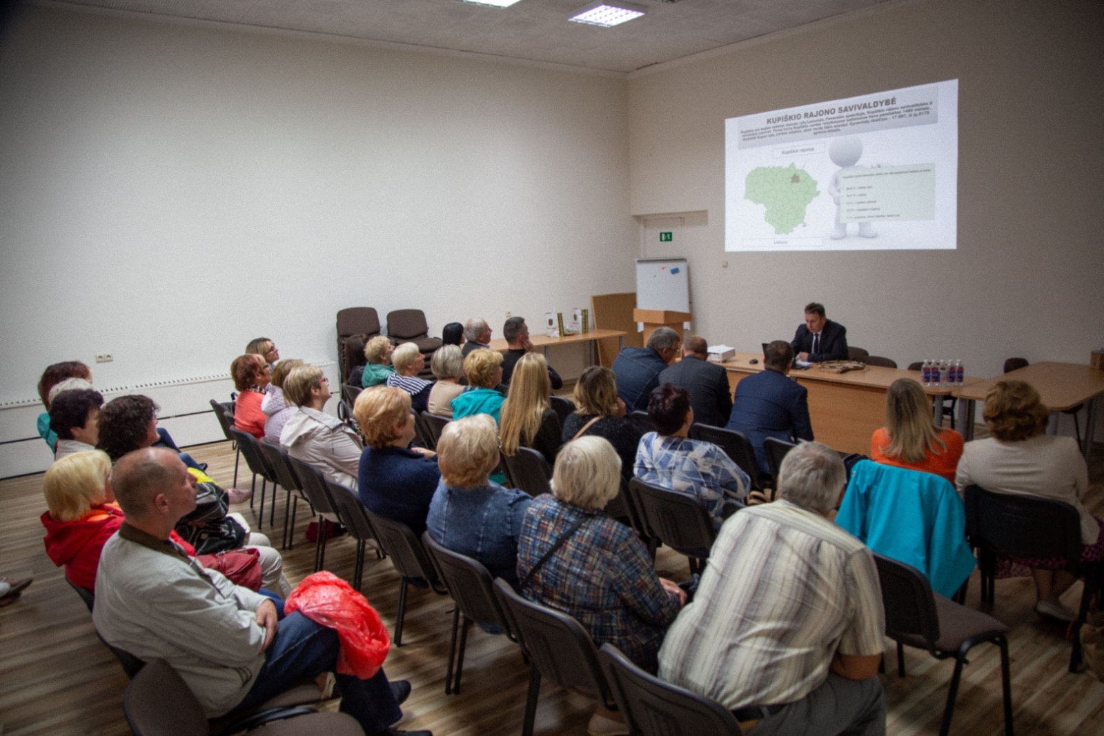 Jēkabpils novada pašvaldības pārstāvji sēž zālē Kupišķos, skatās prezentāciju