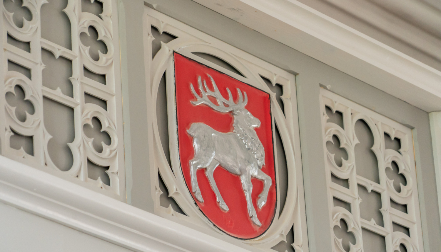 Sēlijas ģerbonis pie baltas koka dekoratīvo elementu sienas