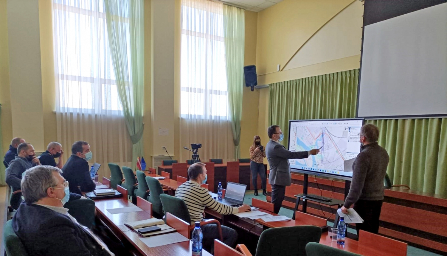 Civilās aizsardzības mācības sēžu zālē Krustpili, tiek rādīta karte uz ekrāna, komisijas locekļi skatās un spriež iespējamās darbības