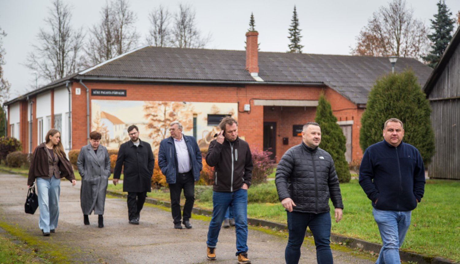 Deputāti iet pret kameru, fonā pagasta pārvaldes ēka