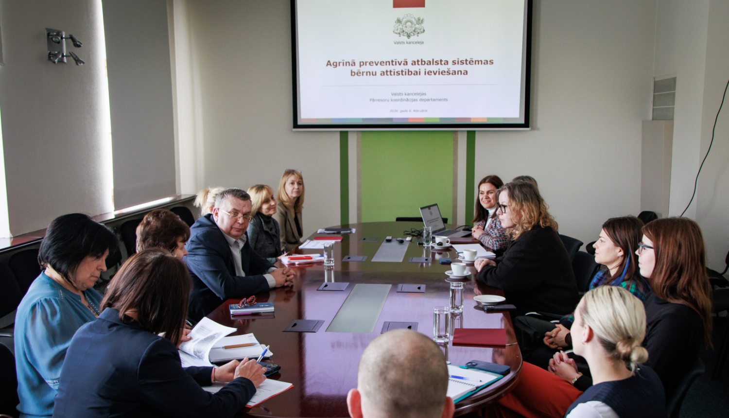 Institūciju pārstāvji sēž pie galda gatavi skatīties prezentāciju
