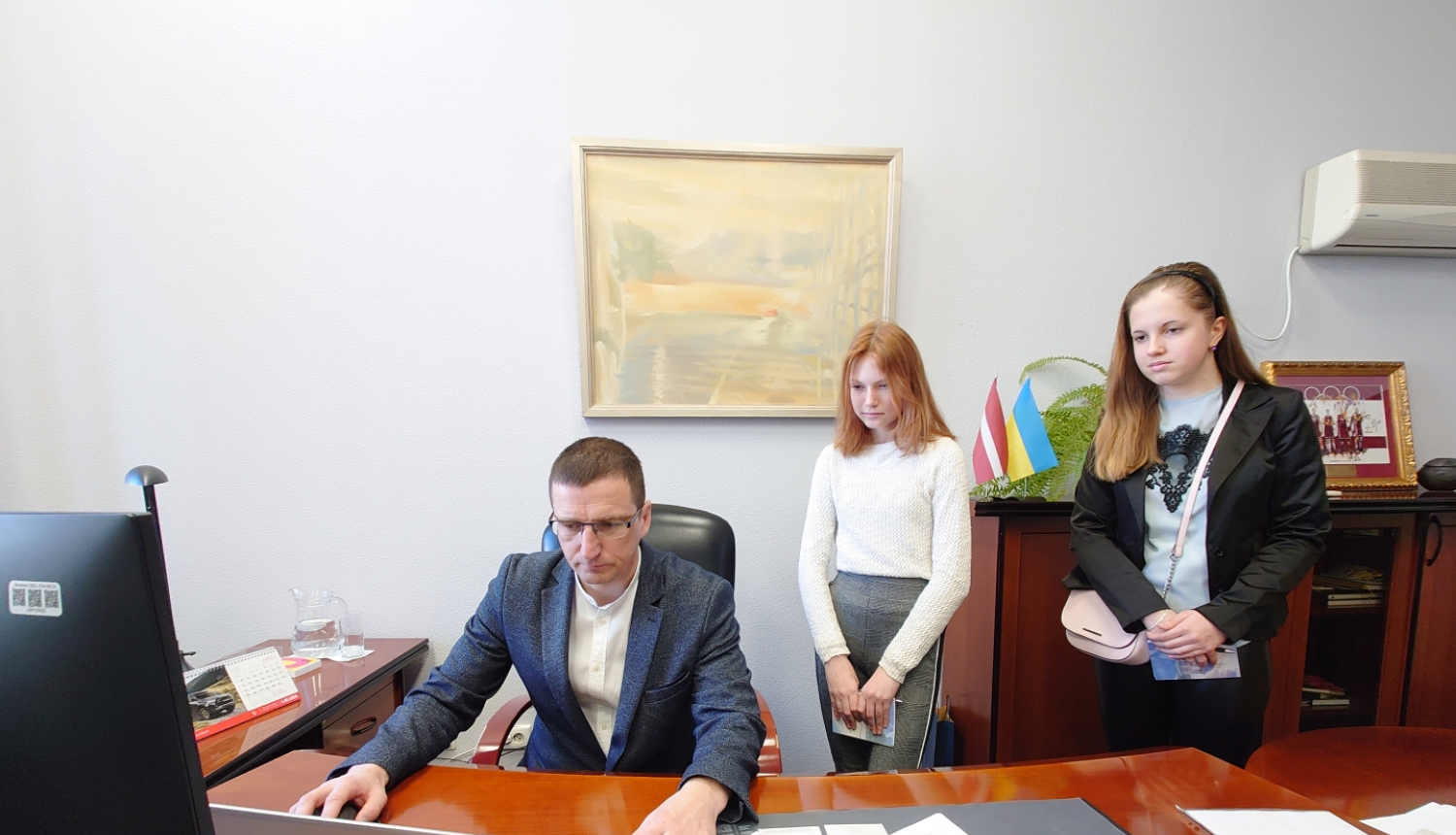 Priekšsēdētājs ar 2 ēnotājiem skolēniem darba kabinetā