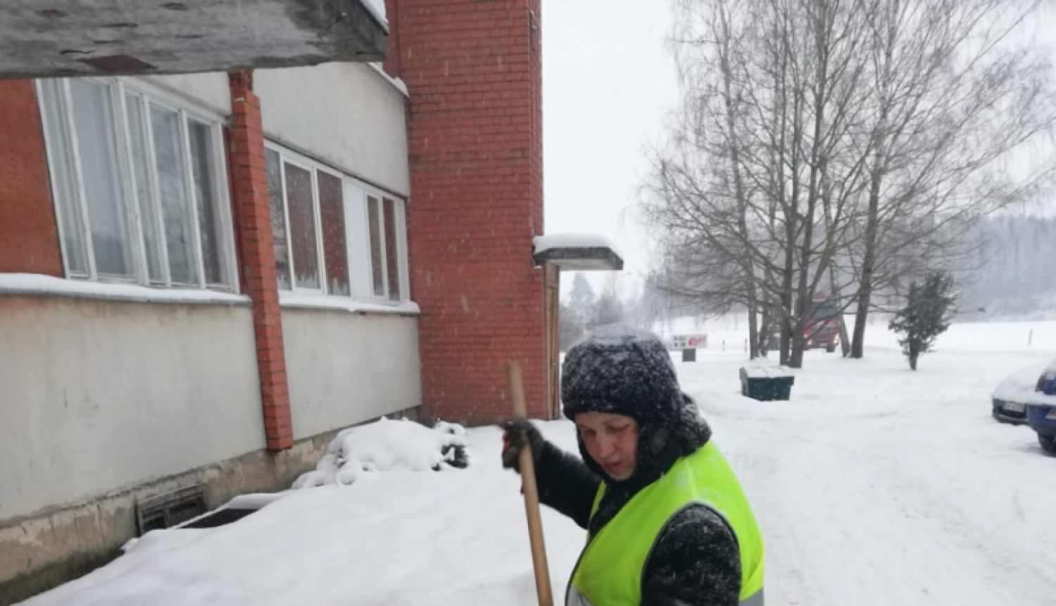 Sētniece slauka sniegu