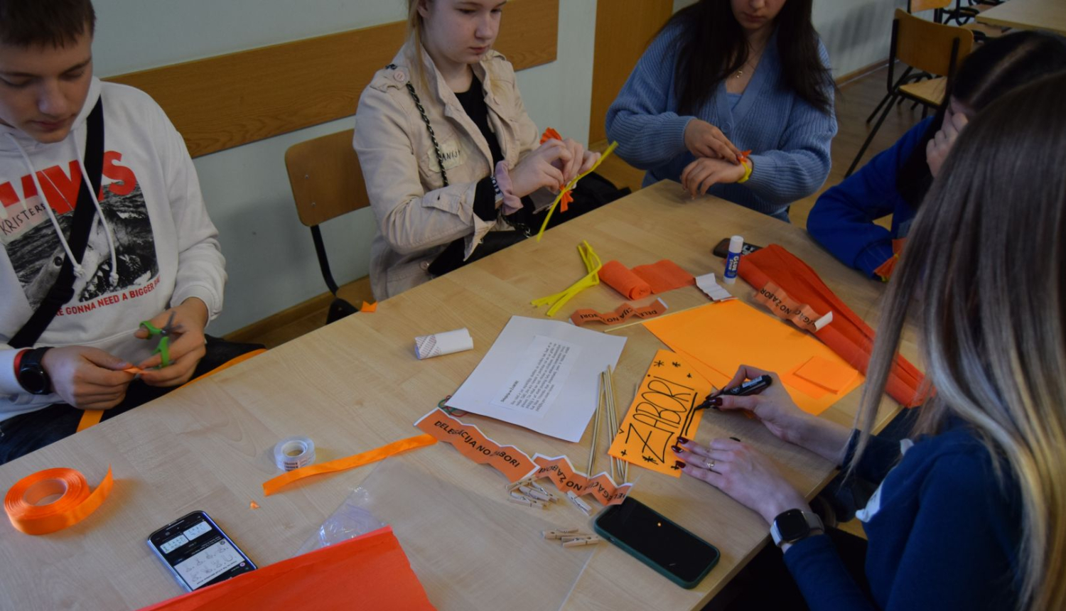 Jaunieši pie galda nodarbojas ar rokdarbiem