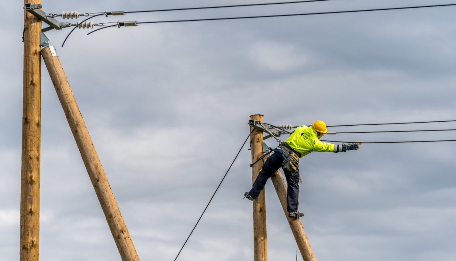fotogrāfijā redzams elektriķis un elektrības stabi