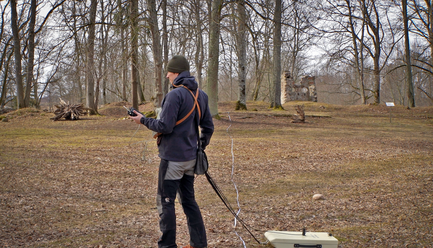 Pētnieks ar ģeoradaru skenē zemi pie Zasas muižas pilsdrupām