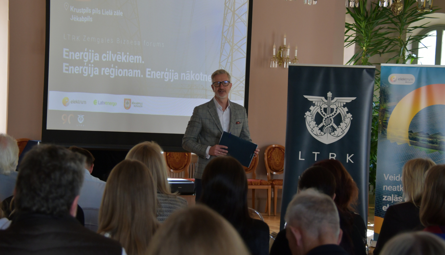 Vadītājs uzrunā publiku zālē