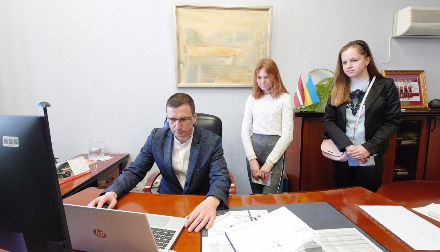 Priekšsēdētājs ar 2 ēnotājiem skolēniem darba kabinetā