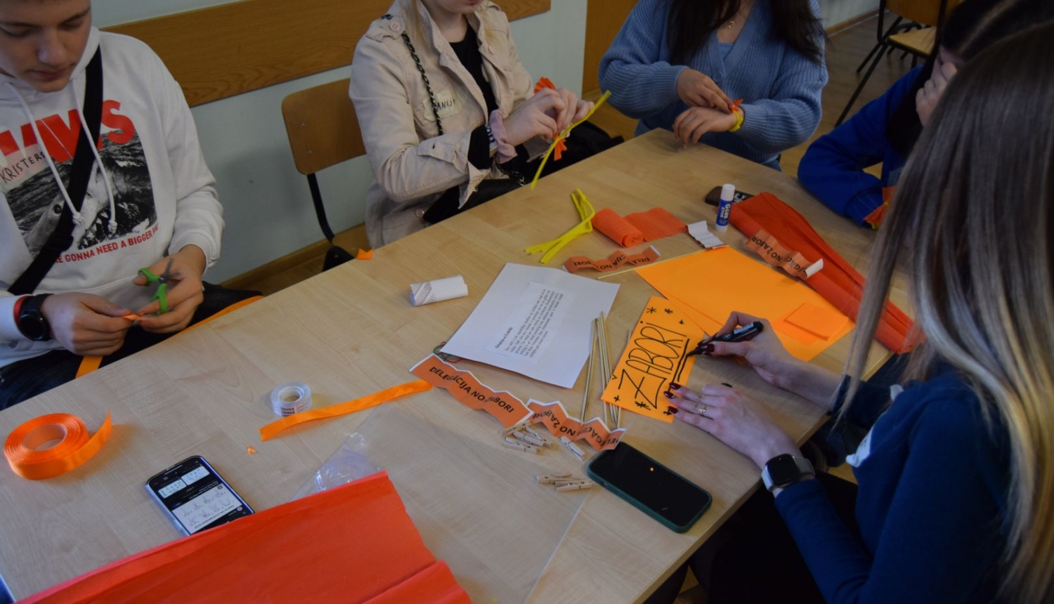 Jaunieši pie galda nodarbojas ar rokdarbiem