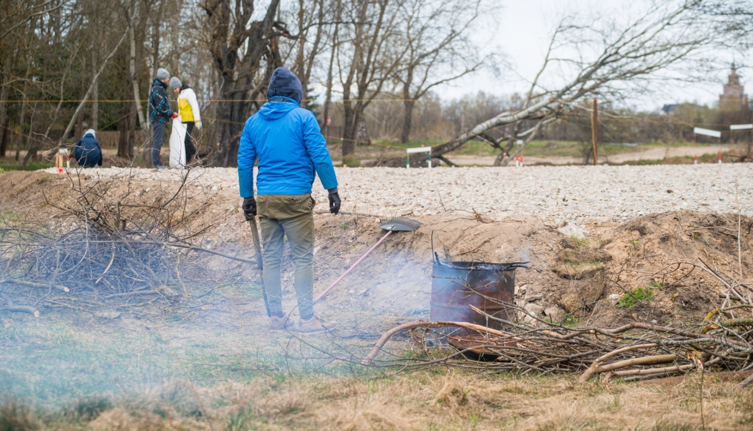 Publicitātes foto no 2021. gada, kurā cilvēks ceļa malā dedzina zaru čupu