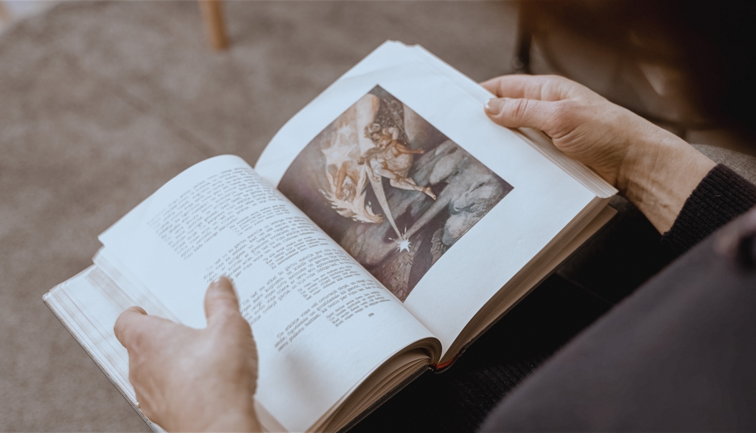 Persona sēžot lasa grāmatu, pār plecu var redzēt tekstu un pasakas ilustrāciju